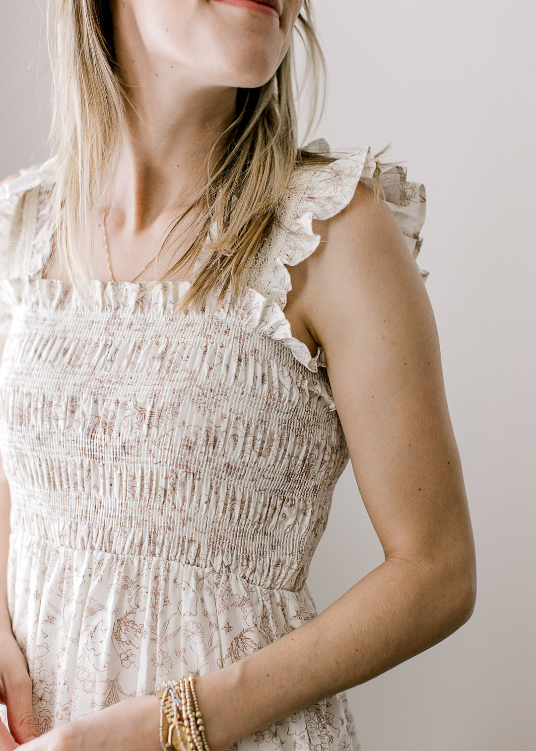 Close up of smocked bodice, square neck and ruffled straps on a cream maxi with bunnies and floral.