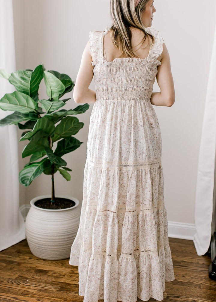 Back view of Model wearing a cream maxi with light brown bunny and floral and wide ruffled straps.