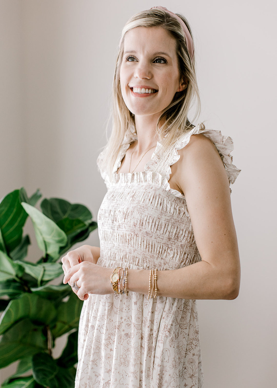 Model wearing a sleeveless cream maxi with light brown bunny and floral and smocked bodice.