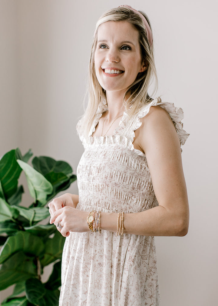 Model wearing a sleeveless cream maxi with light brown bunny and floral and smocked bodice.