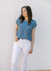 Model wearing a chambray top with capped sleeves and stitching detail at neck, cuff and pocket.