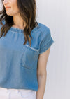 Close up of detail stitching at the neck, cuff and patch pocket on a chambray top. 