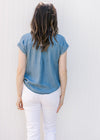 Back view of Model wearing a chambray top with capped sleeves and stitching detail. 