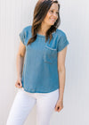 Model wearing white pants and a chambray top with capped sleeves and stitching detail. 