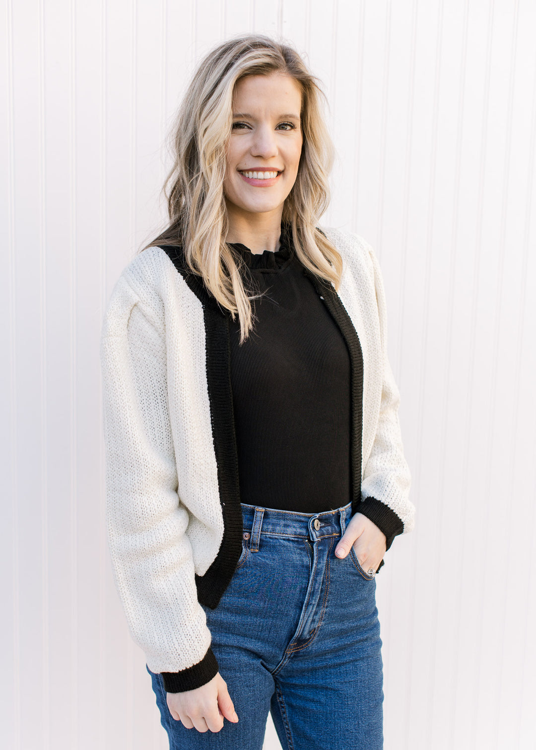 Model wearing jeans with a cream sweater with an open front and a classic fit.