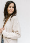 Close up of a model wearing an open front cardigan with long sleeves and ribbed detail. 