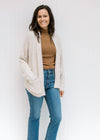 Model wearing a camel top with jeans and a beige open front cardigan with long sleeves. 