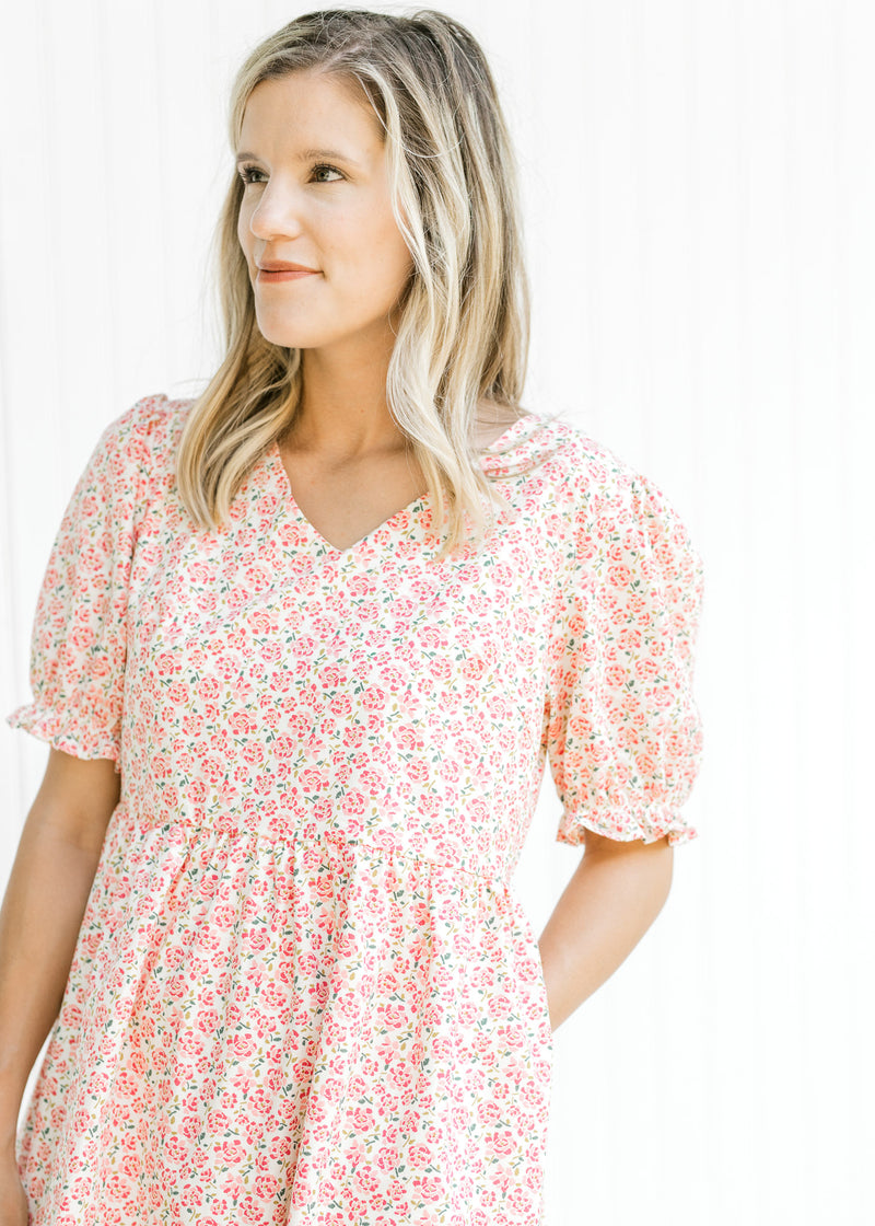 Close up of bubble short sleeves and v-neck on a cream dress with pink microfloral print. 