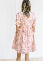 Back view of Model wearing a cream dress with pink microfloral print and short sleeves.