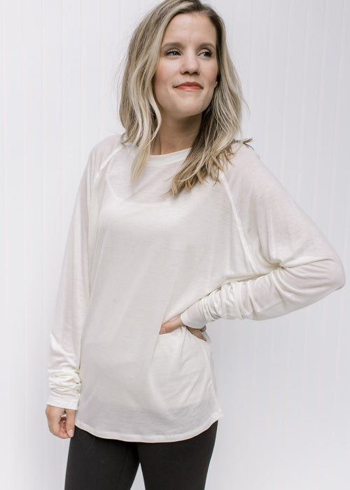Model wearing a classic cream long sleeve top with a round neck and a soft tencel material. 