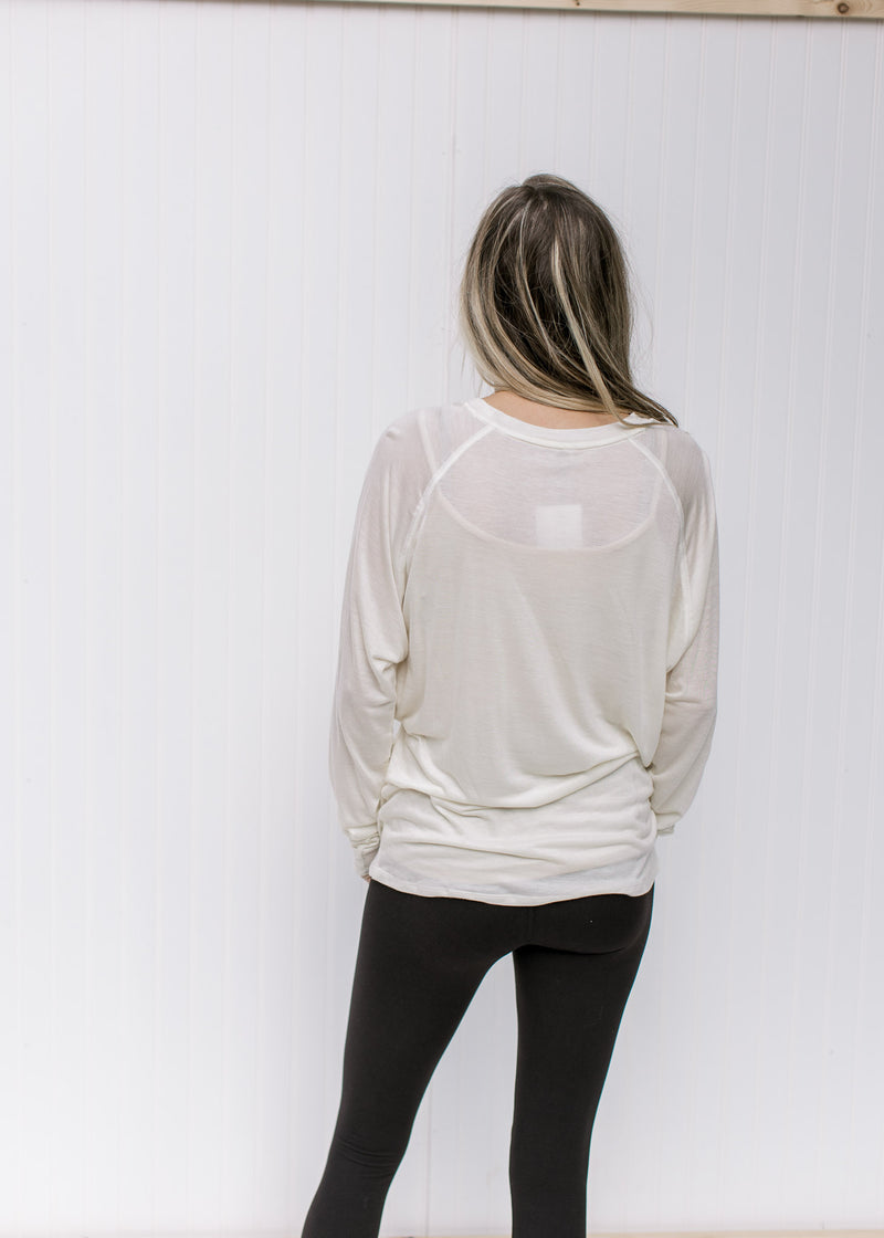 Back view of Model wearing a cream long sleeve top with a round neck and a soft tencel material. 