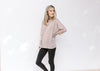 Model wearing black leggings and sneakers with a light purple long sleeve top with a round neck. 