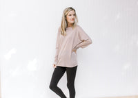 Model wearing black leggings and sneakers with a light purple long sleeve top with a round neck. 