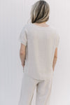 Back view of Model wearing a oatmeal colored short sleeve top with a round neck.