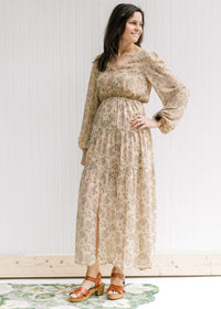 Model wearing a tan lined maxi with microfloral print, sheer long sleeves and a split front. 