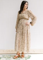 Model wearing a tan lined maxi with microfloral print, sheer long sleeves and a split front. 