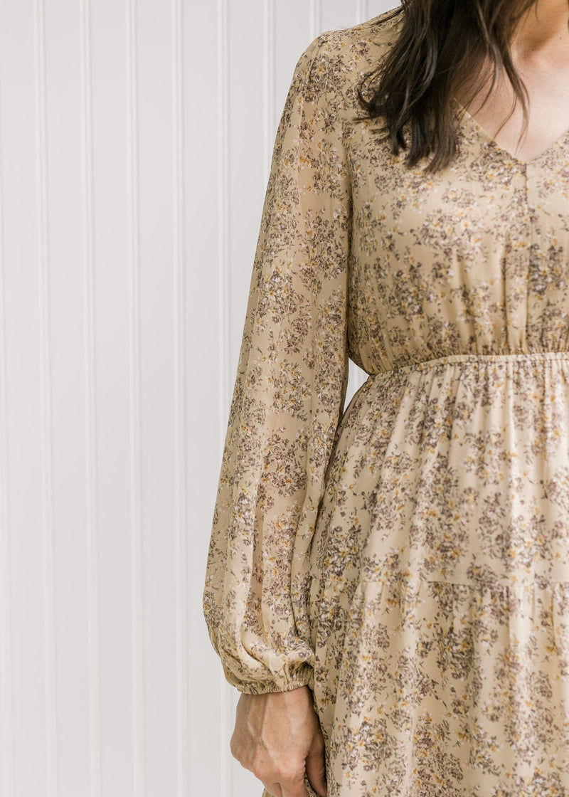 Close up of elastic waist and sheer long sleeves on a tan v-neck maxi with a microfloral print. 