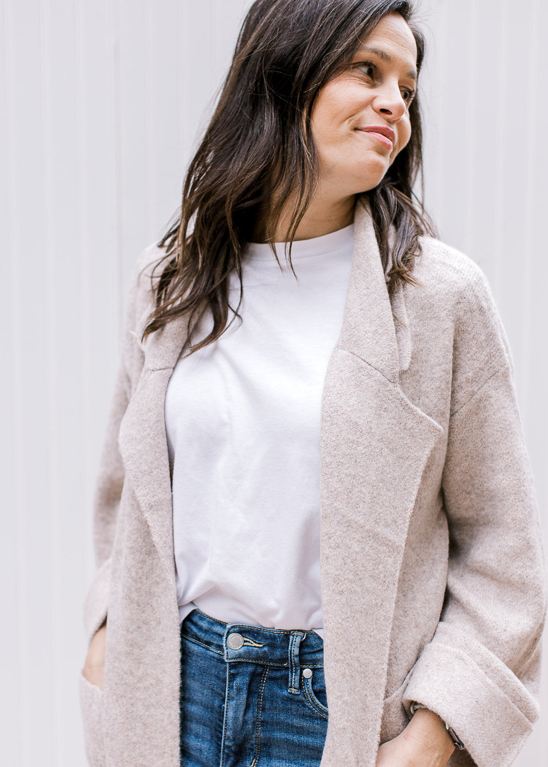 Close up of flap collar and cuffed long sleeves on an oatmeal open front cardigan. 