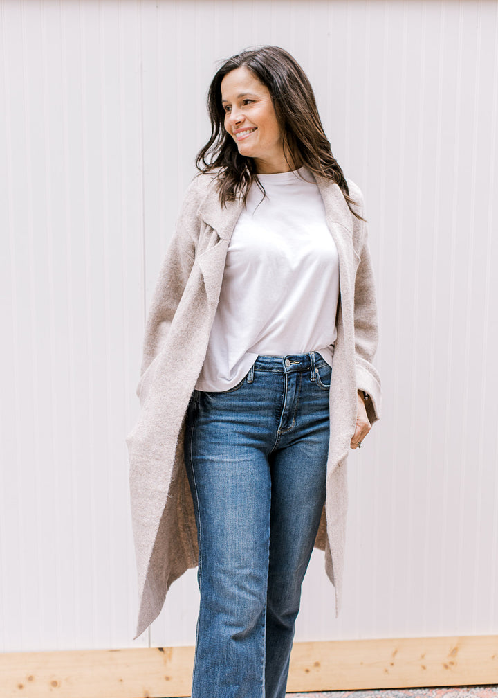 Model wearing an oatmeal open front cardigan with patch pockets and long sleeves with a cuff. 