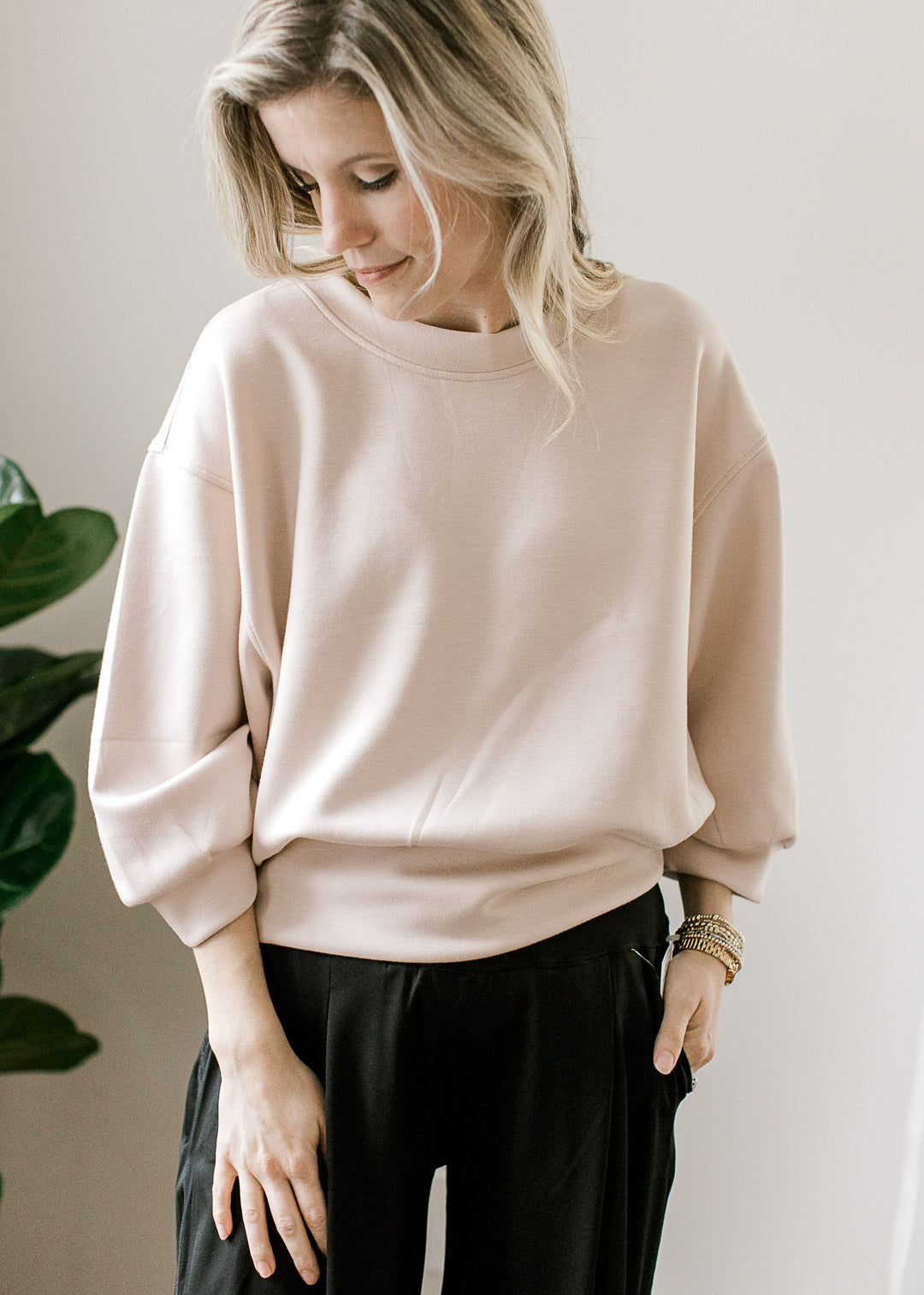 Model wearing a soft pink pullover with a round neck, 3/4 sleeves and a slightly cropped fit.
