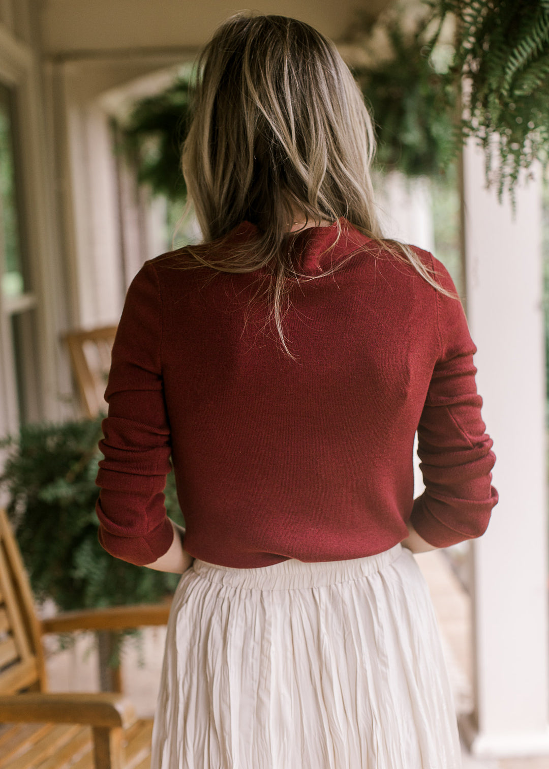 Back view of Model wearing a deep burgundy top with a v-neck and long sleeves. 