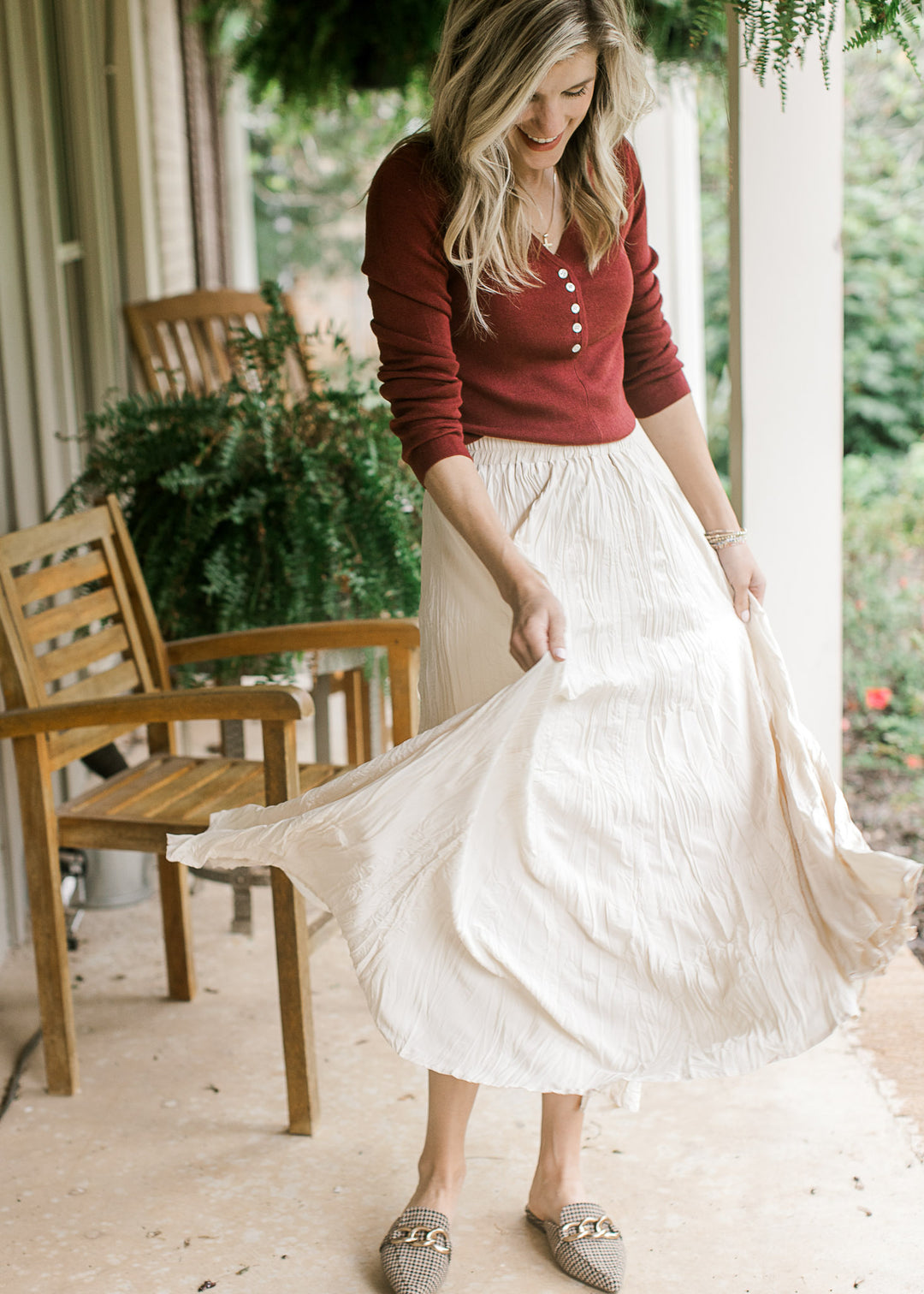 Model wearing a cream maxi and a burgundy top with a v-neck with working buttons and long sleeves. 