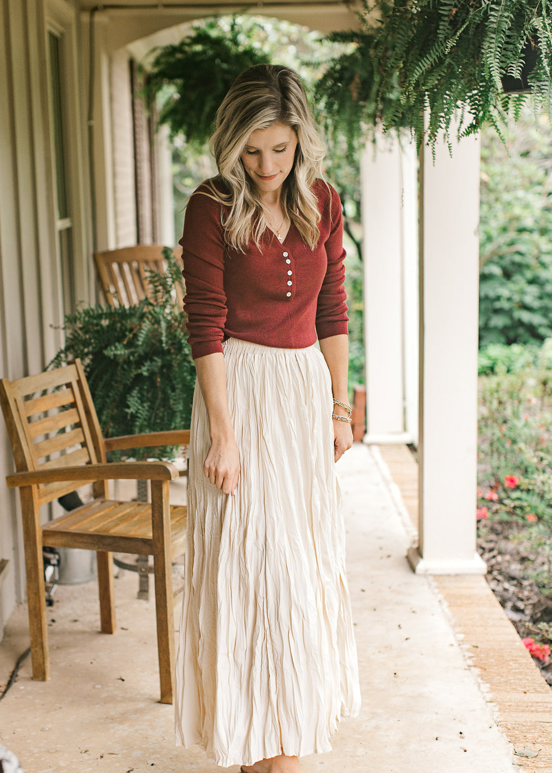 Model wearing a deep burgundy top with a v-neck with working buttons and long sleeves. 