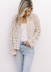 Model wearing jeans and a taupe floral crochet cardigan with a button front and long sleeves. 