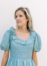 Close up of smocked bodice and ruffle scoop neck on a soft teal above the knee dress.