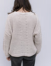 Back view of Model wearing an ivory sweater with long sleeves and an soft polyester material.