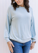 Close up of Model wearing a light blue sweater with a classic fit, long sleeves and a round neck. 