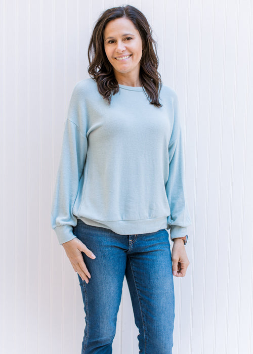 Model wearing a light blue sweater with a classic fit, long sleeves and a round neck. 