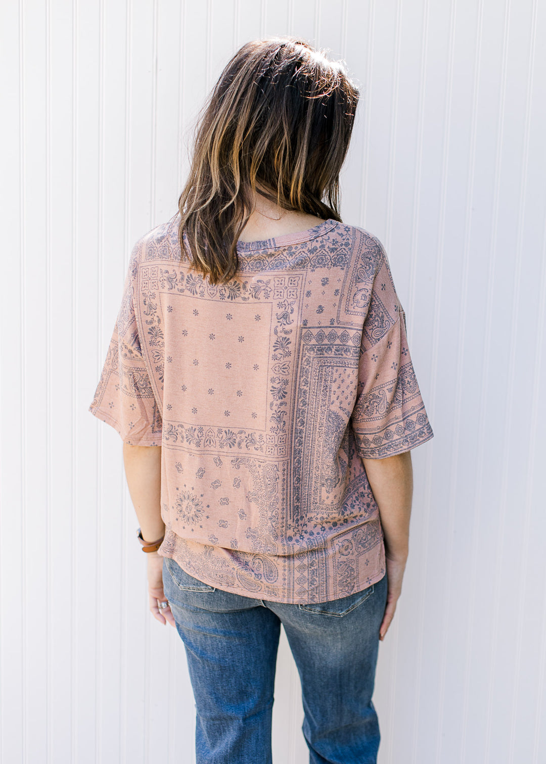 Back view of Model wearing a light brown top with a navy southwestern print and short sleeves.