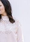 Close up of gold sequins and mock neck on a blush sweater with ribbed cuff, neck and hem. 