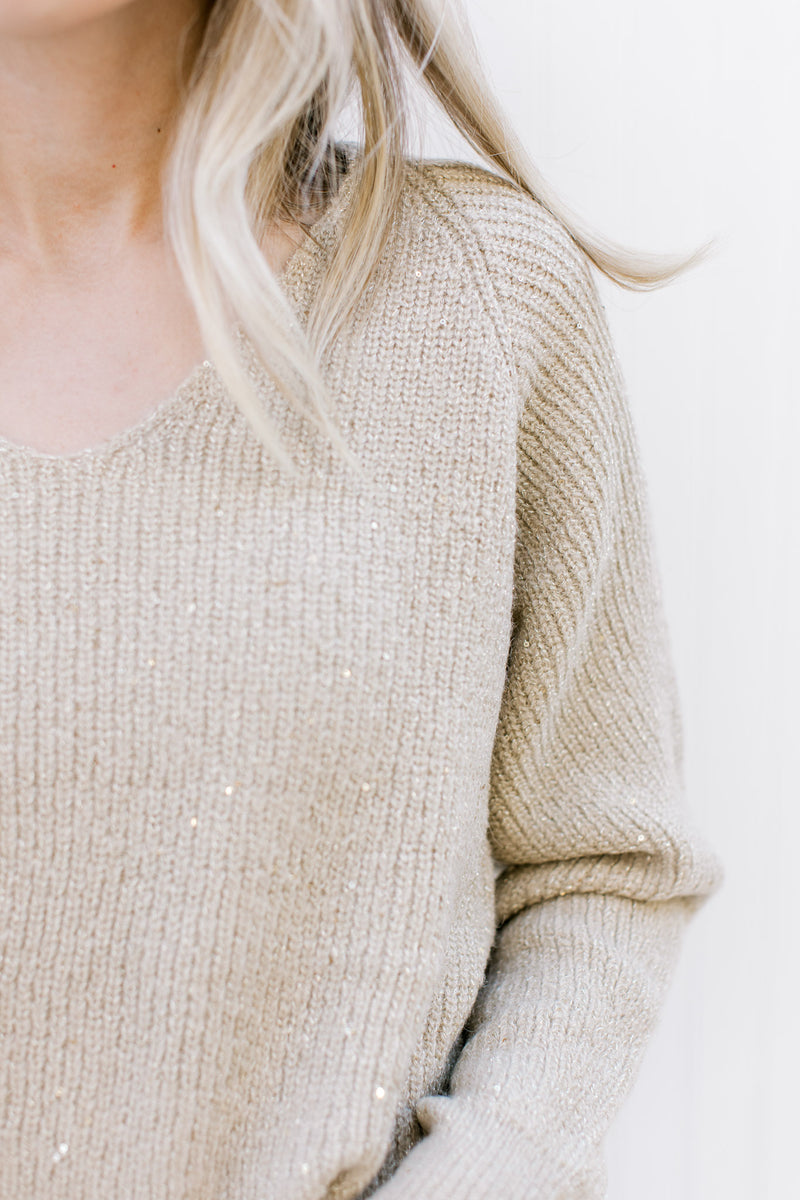 Close up of v-neck on a Model wearing a champagne sweater with long sleeves and woven in sparkles.