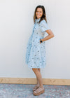 Model wearing wedges with a light blue dress with navy flowers, pockets and short sleeves.