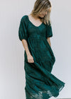 Model wearing a teal, fully lined midi with short bubble sleeves, pockets and a leaf overlay. 