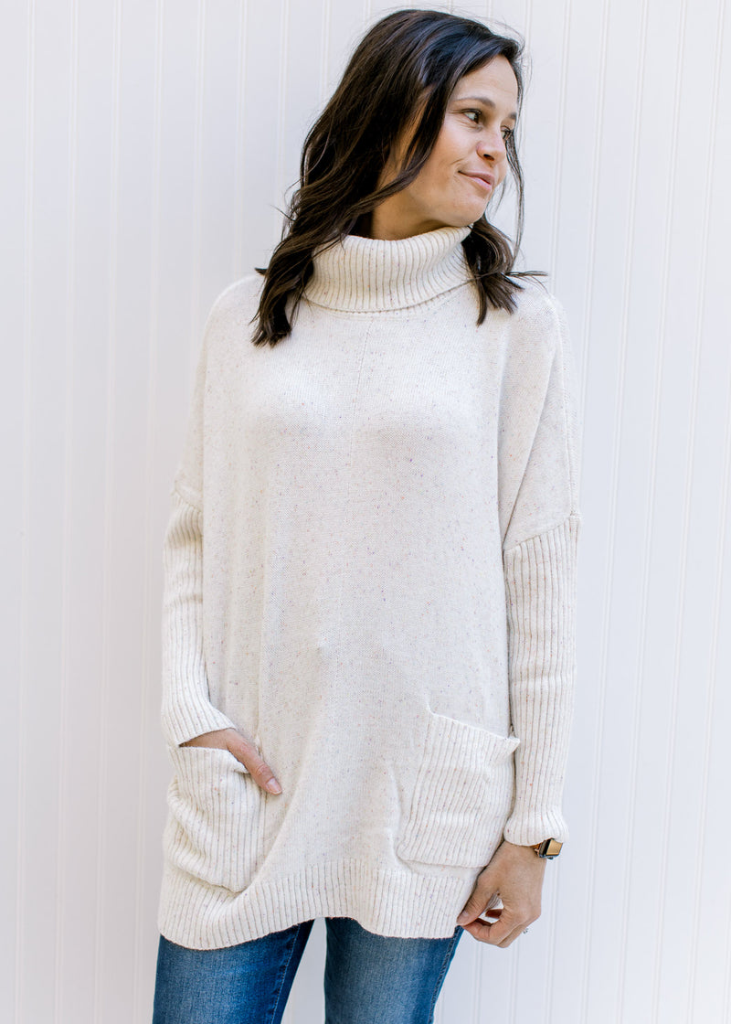 Model wearing an ultra soft, speckled cream knit sweater with a turtleneck and long sleeves. 