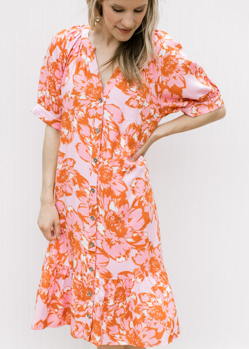Model wearing a light pink dress with pink and orange floral, button front and short sleeves.