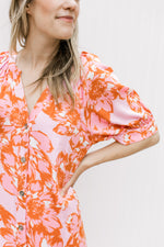 Close up of short sleeve with cuff and button front on a pink midi with pink and orange floral. 