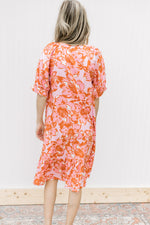 Back view of Model wearing a pink dress with pink and orange floral and short sleeves with cuff.