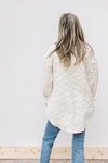 Back view of Model wearing a cream embossed shacket with button closure and patch pockets.