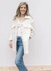Model wearing jeans with a cream embossed shacket with long sleeves and patch pockets.