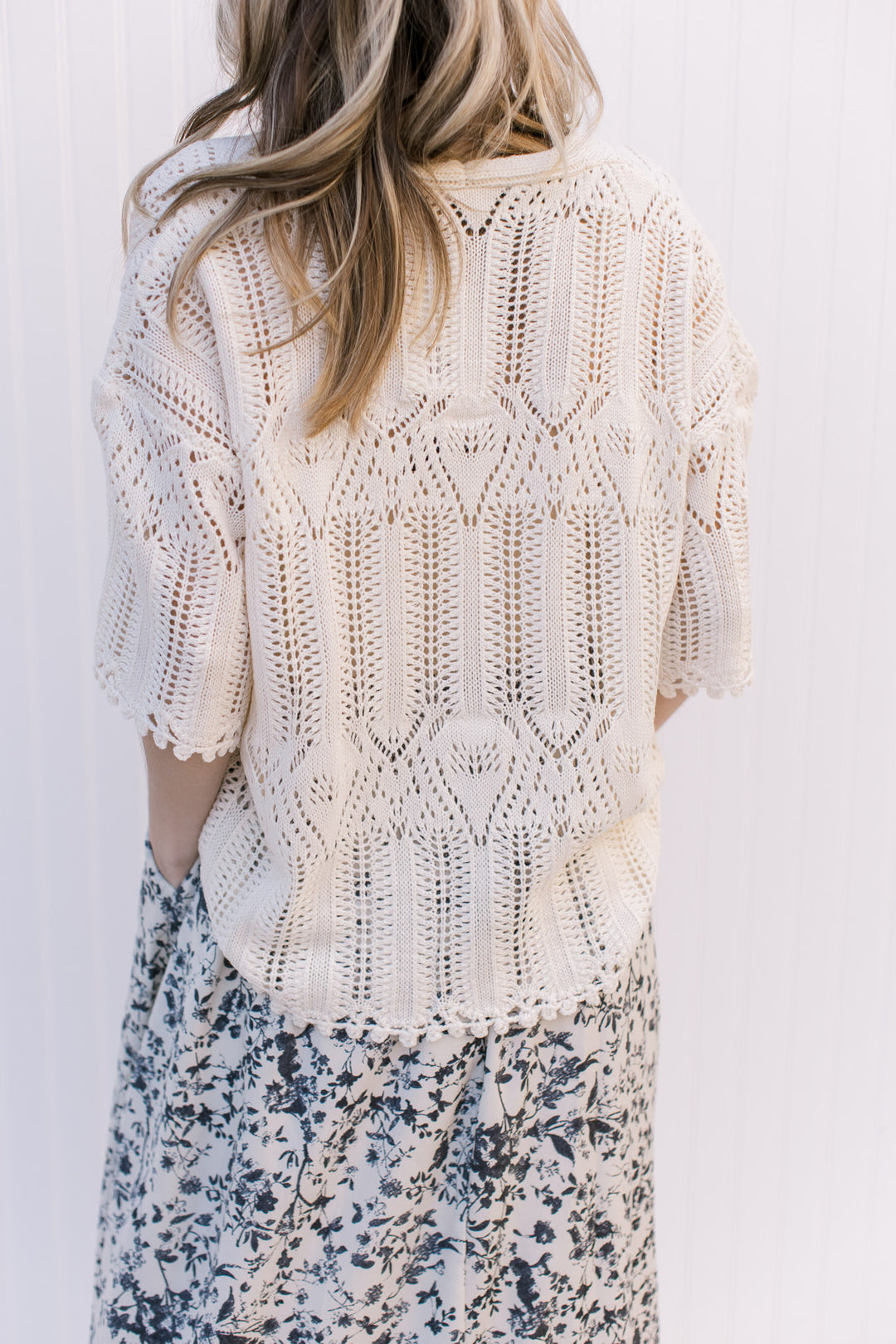 Back view of Model wearing a cream open weave sweater with scalloped hem and sleeve.