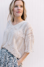 Model wearing a cream open weave sweater with diamond detailing and scalloped hem and sleeve.