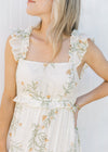 Close up square neckline and ruffle sleeveless on a cream midi with yellow and green floral. 