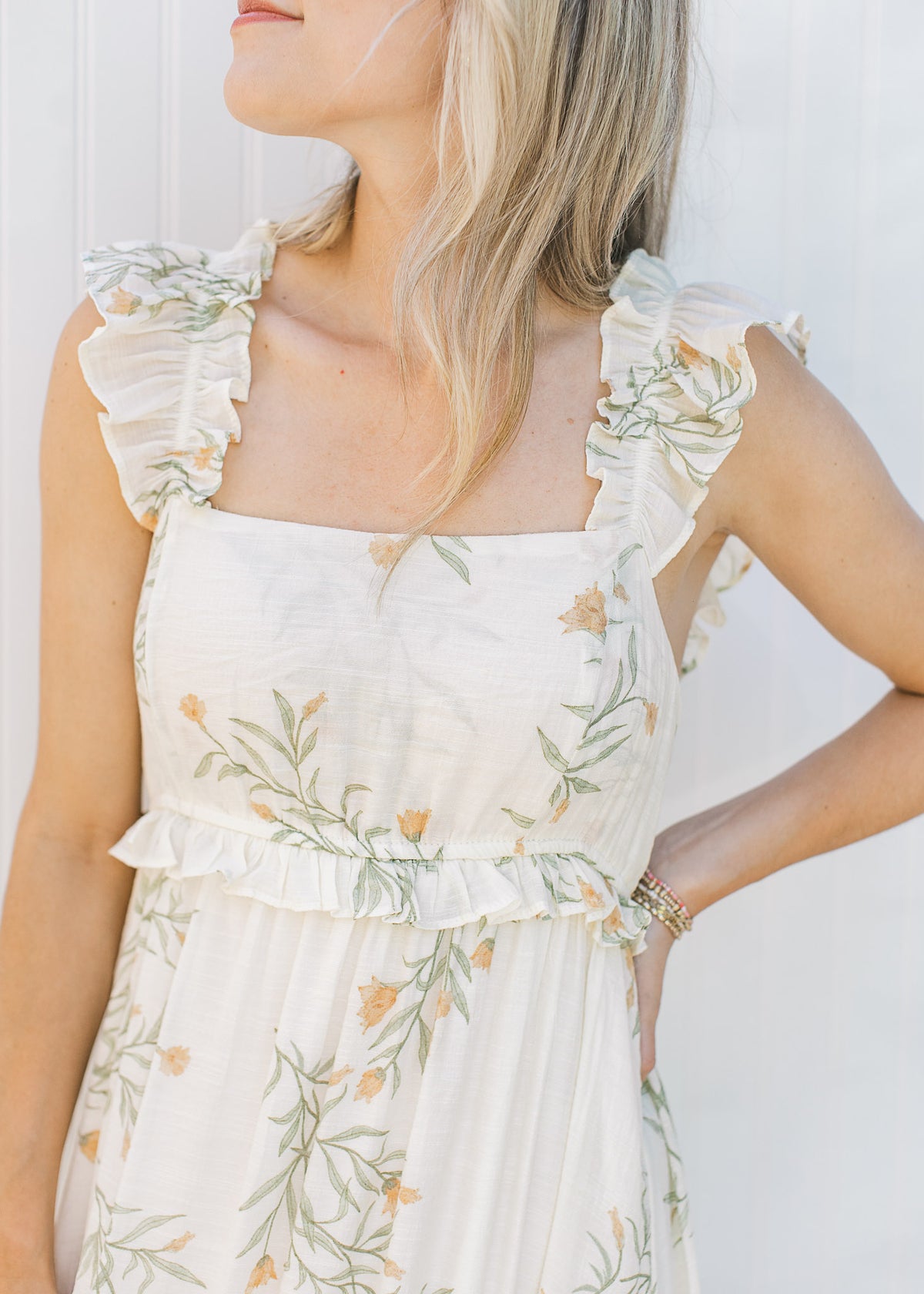 Close up square neckline and ruffle sleeveless on a cream midi with yellow and green floral. 