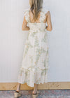Back view of Model wearing a sleeveless, cream midi with floral, smocked back and tired ruffles.
