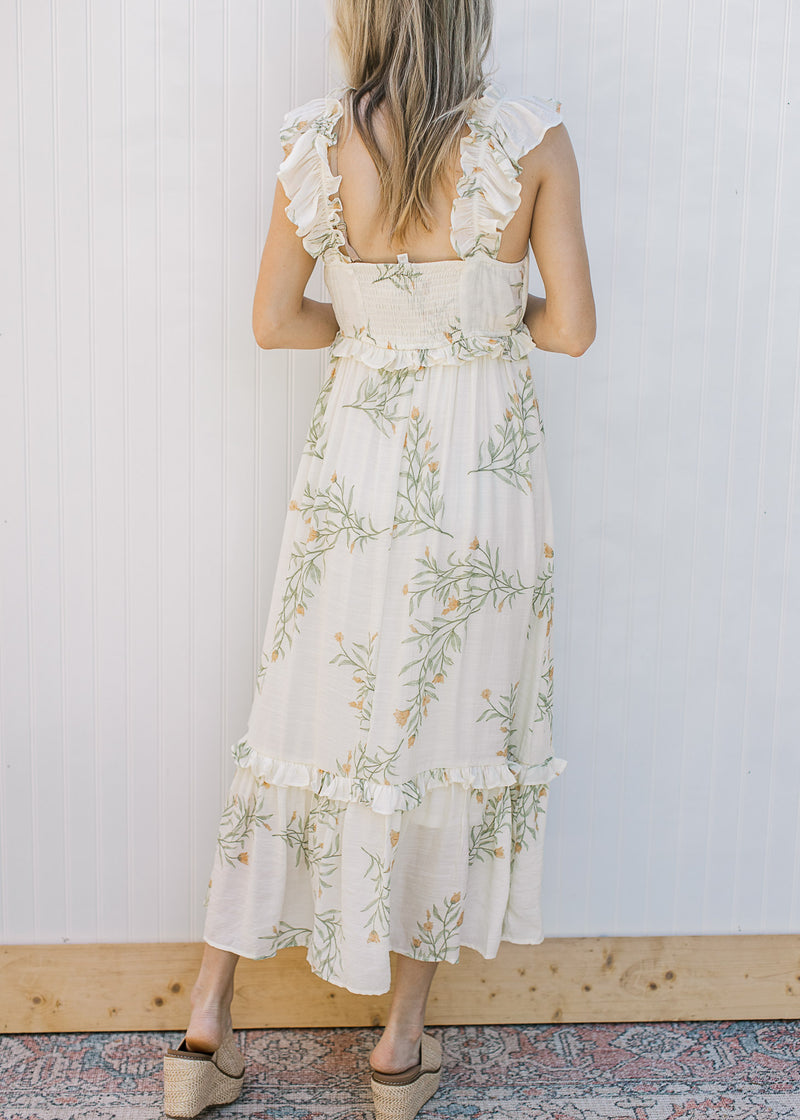 Back view of Model wearing a sleeveless, cream midi with floral, smocked back and tired ruffles.