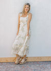 Model wearing wedges and a sleeveless, cream midi with floral, ruffle tiers and a square neck.